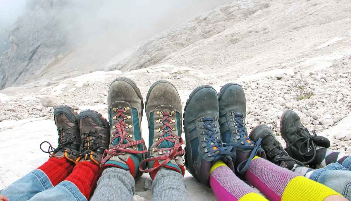 Wanderschuhe von Eltern und Kindern nebeneinander auf Felsen im Gebirge