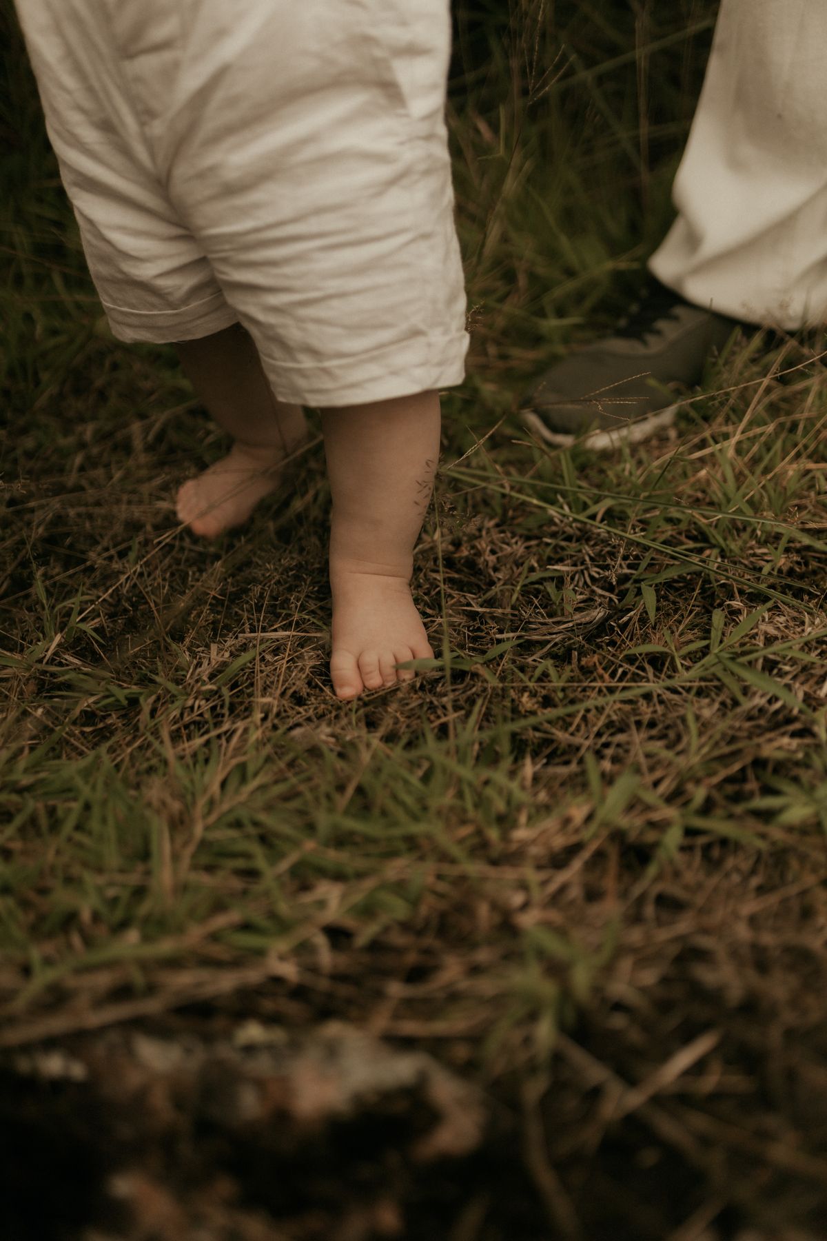 Baby macht barfuß erste Schritte auf einer Wiese