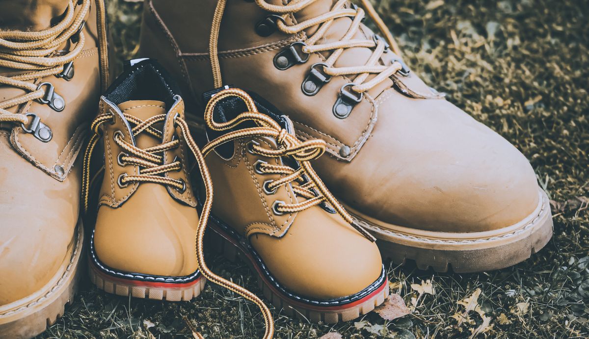 Wanderschuhe von Vater und Kind nebeneinander auf einer Wiese